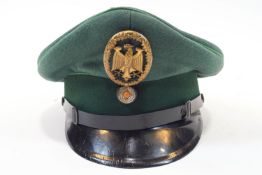 A Third Reich military cap finished in two shades of green set within an eagle in oak leaf surround