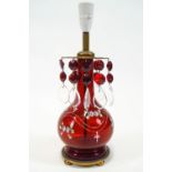 A ruby tinted glass lamp base, painted with bouquets and swags of pearls,