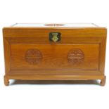 A Chinese hardwood chest, the hinged top with brass lock above a carved panelled front,