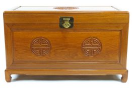 A Chinese hardwood chest, the hinged top with brass lock above a carved panelled front,