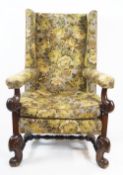 An oak wingback armchair with scroll carved arm supports and legs linked by turned stretchers