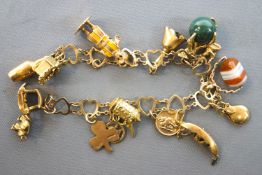 A yellow metal open heart link bracelet having assorted charms. Hallmarked 9ct gold.