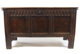 A 17th century oak coffer, the triple panelled front with carved frieze, uprights and apron,