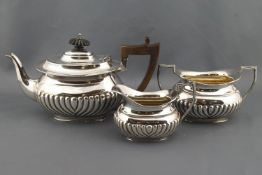 A silver bachelor three piece tea service of bellied half reeded form,