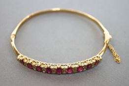 A yellow metal half hoop bangle set with graduated commercial quality rubies