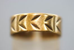 A yellow metal flat profile 6.7mm wedding ring with engraved design.