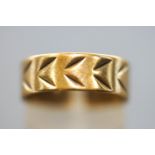 A yellow metal flat profile 6.7mm wedding ring with engraved design.