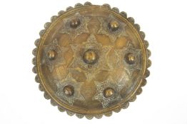 An Islamic brass shield, cast with stars enclosing foliate ornament and bosses,