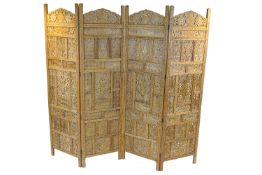 An Indian teak four fold screen, the carved and pierced panels inlaid in brass,