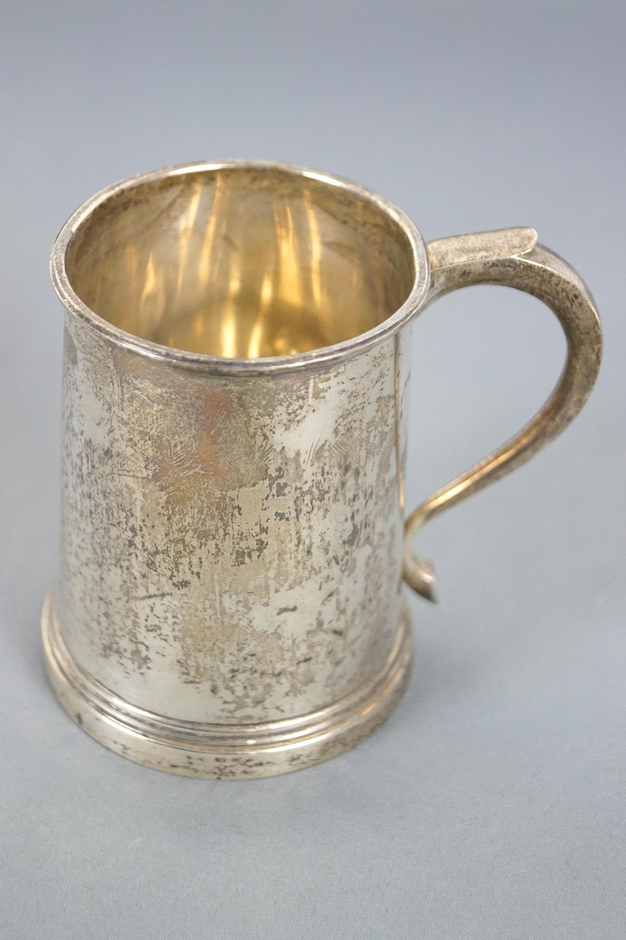 A small silver mug, of plain tapering cylindrical form, with a scroll handle, London 1936, 9cm high,