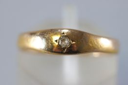 A yellow metal ring set with a single old brilliant cut diamond.