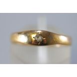 A yellow metal ring set with a single old brilliant cut diamond.