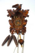 A SWiss carved wood musical cuckoo clock carved with leaves, two woodpeckers and a bird,