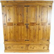 A 20th century custom made pine wardrobe, with four panelled doors above two drawers,