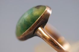 A yellow metal ring set with an oval cabochon nephrite jade measuring approximately 15.3mm x 7.7mm.