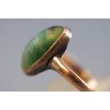 A yellow metal ring set with an oval cabochon nephrite jade measuring approximately 15.3mm x 7.7mm.