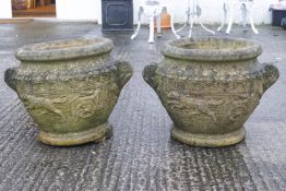 A pair of reconstituted stone urns, decorated with charioteer design, 40cm high,