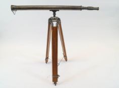 A silvered brass field telescope on a teak extending tripod base,