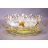 An opaline and gilt glass finger bowl and stand, of frilled form, gilt with rose sprays,