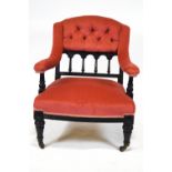 A late Victorian armchair with ebonised frame, button back,