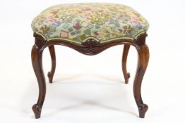 A Victorian mahogany stool, of scroll outline, with stuff over seat, on four cabriole legs,