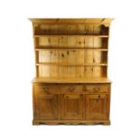 A 20th century pine dresser, the base with three drawers above three conforming panelled doors,