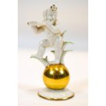 A Hutschenreuther porcelain figure of a cupid playing a flute standing on a gilt ball on flared