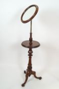 A Victorian mahogany washstand, the tilting round mirror on tilting hinge above a round shelf,