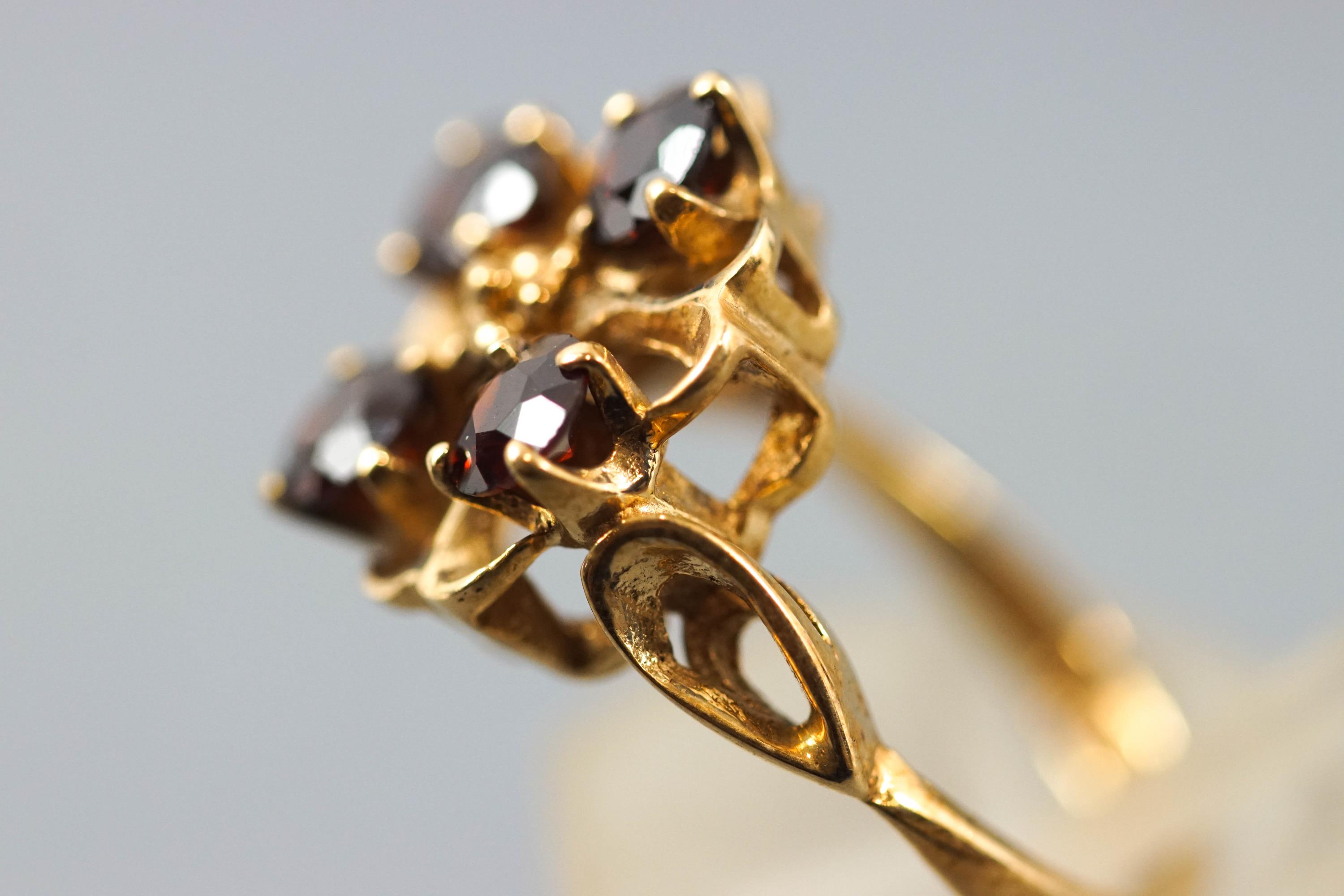 A yellow metal dress ring set with four round faceted cut garnets. - Image 2 of 3