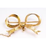 A yellow metal bow brooch with engraved finish. Pin and C catch fittings.