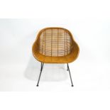 A rattan armchair, circa 1960, on four black lacquered metal legs,