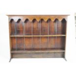 An oak plate rack, with two shelves below a scrolled hanging apron and moulded top,