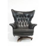 A G-plan swivel 'Blofeld, armchair, circa 1960, button back upholstered in black fabric,
