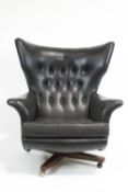 A G-plan swivel 'Blofeld, armchair, circa 1960, button back upholstered in black fabric,