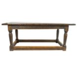 An oak refectory table, the plank top above a carved interlocking scroll frieze,