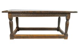 An oak refectory table, the plank top above a carved interlocking scroll frieze,