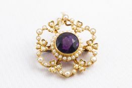 A yellow metal cluster pendant principally set with a round faceted cut amethyst