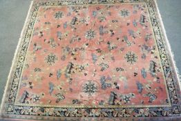 A Chinese style carpet with an overall pattern of repeating motifs on a pink ground within a wide