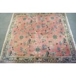 A Chinese style carpet with an overall pattern of repeating motifs on a pink ground within a wide