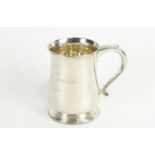 A silver mug of traditional baluster form, with scroll handle, raised on a stepped foot,