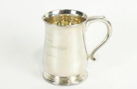 A silver mug of traditional baluster form, with scroll handle, raised on a stepped foot,
