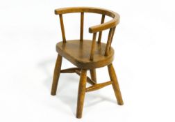 An elm child's chair, with convex spindle back, on turned plain legs and stretchers,