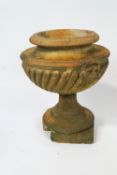 A terracotta garden urn of gadrooned form with lion's masks,