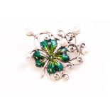 A white metal brooch in the design of a clover with green enamelled finish