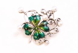 A white metal brooch in the design of a clover with green enamelled finish