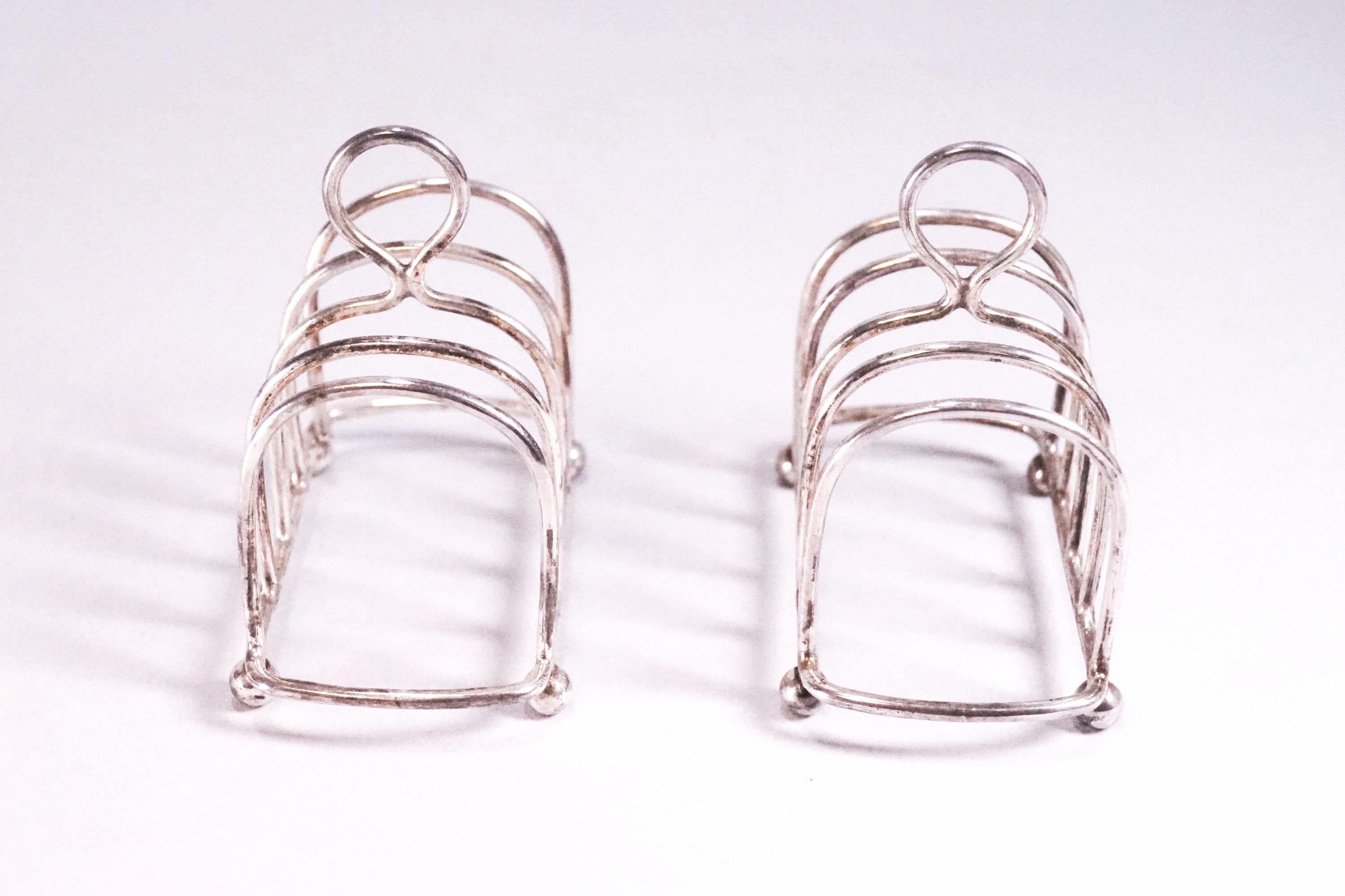 A pair of silver miniature form plain round arch toast racks with loop handles, raised on ball feet, - Image 2 of 2