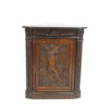 An oak corner cupboard, the panelled hinged door carved with an angel,