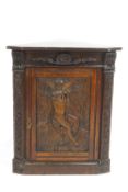 An oak corner cupboard, the panelled hinged door carved with an angel,