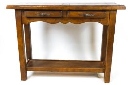 An oak console table with two frieze drawers, the square tapering legs linked by a shelf,