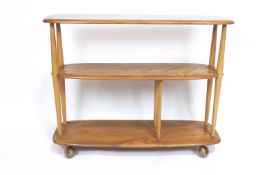 An Ercol light elm three tier shelving unit/bookcase, on castors,